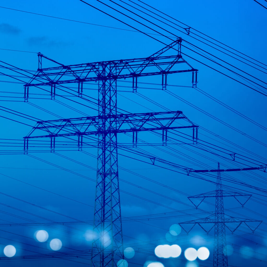 high-voltage tower and power lines with abstract defocused city lights at night, transmission of electricity for urban life